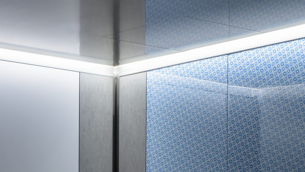 Modern elevator lighting design showing a sleek gray cab interior with integrated perimeter lighting and downlights.