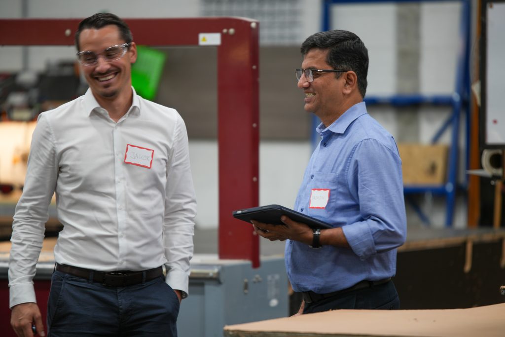 Two men smiling and conversing with a tablet during SnapCab's Continuous Improvement Tour